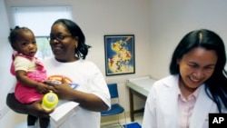 FILE - Jaliyah Smith, 13-month-old niece of Felicia Sykes of Starkville, Miss., gets a checkup by Dr. Minerva Rasalan, April 25, 2007, in West Point, Miss. For many foreign trained doctors, practice in the U.S. provides better pay and working conditions.