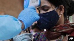 A child looks at his mother being screened for COVID-19 symptoms at an apartment complex in Mumbai, India, July 28, 2020.