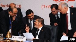 Egyptian President Mohamed Morsi (C) chatting with officials during the closing session of the 12th summit of the Organization of Islamic Cooperation (OIC) in Cairo, February 7, 2013.