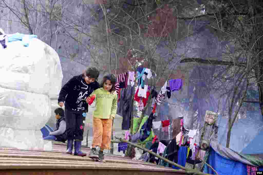 Two refugee kids walk on top of piled up rusty iron railings at Idomeni camp. (Jamie Dettmer for VOA)