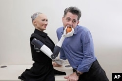 FILE - David Hanson, the founder of Hanson Robotics, poses with his company's flagship robot, Sophia, a lifelike robot powered by artificial intelligence, in Hong Kong, Sept. 28, 2017.