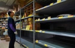 A worker checks an empty shelf for rice at a supermarket in Hong Kong, Feb. 6, 2020.