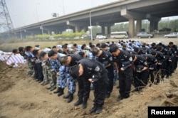 Representatives from the police and People's Liberation Army (PLA), marking the seventh day since the Tianjin explosions, pay tribute to the people who died, in a ceremony at Binhai new district, Tianjin, China, Aug. 18, 2015.