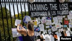 지난달 27일 미국 뉴욕 브루클린의 더그린우드 묘지 밖에 설치된 임시 추모지에서 여성이 신종 코로나바이러스 감염증(COVID-19)으로 숨진 희생자의 이름을 적고 있다. 