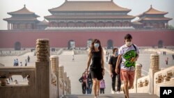 Para pengunjung mengenakan masker untuk melindungi dari penularan virus corona di Kota Terlarang, Beijing, 1 Mei 2020. (Foto: AP) 