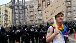 Seorang aktivis LGBTQ tampak berdiri di dekat rombongan polisi yang mengawal aksi pawai Pride di ibu kota Ukraina, Kiev, pada 19 September 2021 (Foto: AFP/Sergei Supinsky)