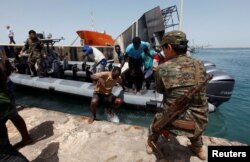 FILE - Migrants arrive at a naval base after they were rescued by the Libyan coast guard in the coastal city of Tripoli, Libya, May 6, 2017.