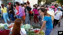 រូបថតឯកសារ៖ កម្មករ​រោងចក្រ​កាត់​ដេរ​ម្នាក់​កំពុង​ទិញ​បន្លែ​ ដើម្បី​ចម្អិន​ម្ហូប​ពេល​ល្ងាច​ ក្រោយ​ពេល​ចេញ​ពី​ធ្វើ​ការ នៅ​ក្បែរ​រោងចក្រ​មួយនៅ​ទីក្រុង​ភ្នំពេញ ថ្ងៃពុធ ទី១២ ខែ​វិច្ឆិកា ឆ្នាំ២០១៤។ (ហេង ស៊ីនិត/AP)