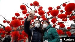 Visitors wearing face masks against pollution take pictures of themselves at the temple fair at Ditan Park (the Temple of Earth) as the lunar new year of the rooster is celebrated, in Beijing, China, Jan. 28, 2017