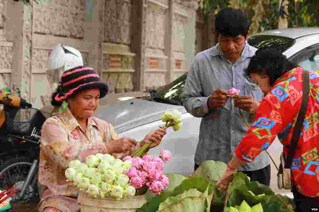 អ្នកលក់ផ្កាសម្រាប់បូជាព្រះ នៅមុខវត្តកោះ នៅថ្ងៃបិណ្ឌមួយ កាលពីថ្ងៃទី២៨ ខែកញ្ញា ឆ្នាំ២០១៥។ (ឡេង ឡែន/VOA)