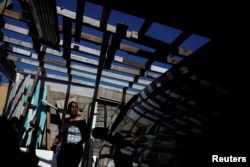 Milagros Jimenez helps her husband to rebuild their house, which was partially destroyed by Hurricane Maria, at the squatter community of Villa Hugo, Dec. 11, 2017.