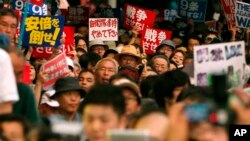 15일 일본 도쿄에서 집단자위권에 반대하는 시위대가 '전쟁 반대', '아베 반대' 등 푯말을 들고 거리행진을 하고 있다.