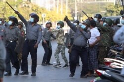 A policeman aims a slingshot towards an unknown target during a crackdown on anti-coup protesters holding a rally in front of the Myanmar Economic Bank in Mandalay, Feb. 15, 2021.
