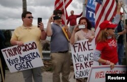 A man watches people cheer as U.S. President Donald Trump passes by in his motorcade on his way to his Mar-A-Lago club in Palm Beach, Florida, Feb. 3, 2018.