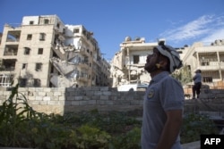 FILE - A rescuer looks towards the sky following an airstrike in the rebel-held Ansari district in the northern Syrian city of Aleppo, Sept. 23, 2016.