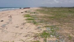 This video grab from an AFPTV video taken on March 27, 2021 shows people picking up plastic waste at Lighthouse Beach in Lagos. -