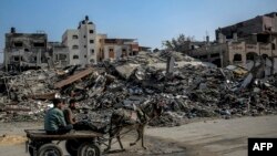 26일 가자지구 북부 이스라엘군 공습 잔해 곁에서 팔레스타인인들이 당나귀 수레를 타고 이동하고 있다. 
