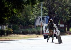 An armed soldier turns away a vehicle during lockdown in Harare, Zimbabwe, April 13, 2020, in an effort to curb the spread of the coronavirus.