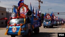 ការដង្ហែរ​ក្បួន​ឃោសនា​រក​សម្លេង​ឆ្នោត​របស់​គណបក្ស​ប្រជាជន​កម្ពុជា ដែល​មាន​រថយន្ត​និង​ម៉ូតូ​ដែល​មាន​ដោត​ទង់ជាតិ​នៃ​ព្រះរាជាណាចក្រ​កម្ពុជា​និង​ទង់​គណបក្ស​រូប​ទេវតា​បាច​ផ្កា​នៅ​ចំ​កណ្តាល​ផ្ទាំង​ក្រណាត់​ពណ៌​ផ្ទៃមេឃ។