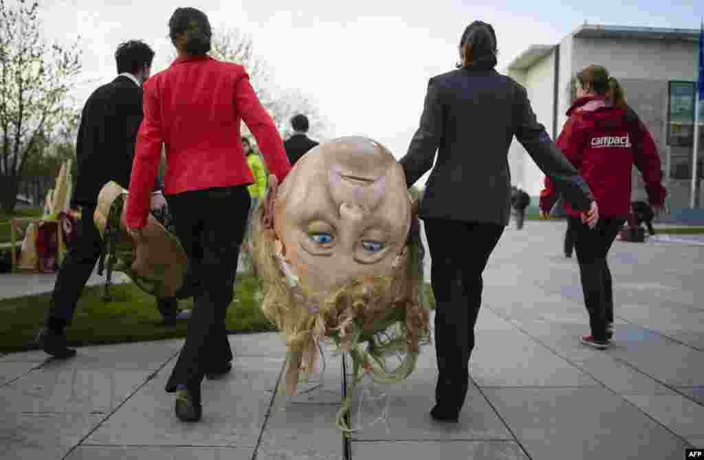 Activists of BUND and Campact ecological associations carry a giant head featuring German Chancellor Angela Merkel before a demonstration against the reform of the Renewable Energy Sources Act (EEG) in front of the Chancellery in Berlin.