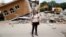 FILE - Ana Maria Hernandez, 37, a clothing salesperson, stands outside her house as it is demolished after an earthquake in Jojutla de Juarez, Mexico, Sept. 30, 2017. 