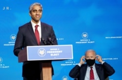 President-elect Joe Biden, right, puts on his mask as he listens to Dr. Vivek Murthy, who has been nominated by Biden to serve as U.S. Surgeon General, speak during an event at The Queen theater in Wilmington, Delaware, December 8, 2020.