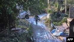 Seseorang melewati jalan yang dilanda banjir dekat sebuah rumah di mana sembilan orang meninggal akibat air meluap dari sungai di Casteldaccia dekat Palermo, Sisilia (4/11).