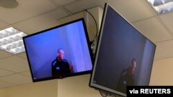 FILE - Russian opposition leader Alexey Navalny is seen on screens via video link before a hearing, in Moscow, Russia, April 29, 2021. (Press Service of Babushkinsky District Court of Moscow/Handout via Reuters)