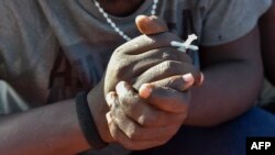 Un migrant serre dans ses mains une croix, le 13 avril 2013.