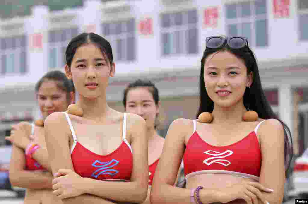 Peserta kontes kecantikan pariwisata mengatur keseimbangan telur-telur yang diletakkan di tulang selangka mereka sambil berjalan di sepanjang Yellow River di Jiyuan, provinsi Henan, China, 22 Juni 2015. Para kontestan yakin bahwa bila mereka cukup langsing, tulang selangka mereka akan bisa menjaga keseimbangan telur-telur tersebut.