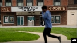 A person jogs past a movie theater temporarily closed due to the coronavirus outbreak April 6, 2020, in St. Louis.