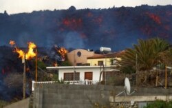 FILE - A house burns due to lava following the eruption of Cumbre Vieja Volcano, on the Canary Island of La Palma, Spain, Oct. 27, 2021.