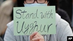 FILE - A man holds a sign during a rally to show support for Uighurs and their fight for human rights in Hong Kong, December 22, 2019. 