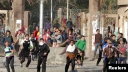 FILE - Students of Al-Azhar University, who are supporters of the Muslim Brotherhood and deposed Egyptian President Mohamed Morsi, clash with riot police and residents in Cairo's Nasr City, Jan. 8, 2014. 