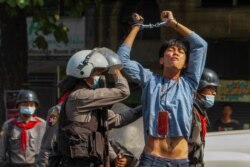 A pro-democracy protester is detained by riot police officers during a rally against the military coup in Yangon, Myanmar, February 27, 2021.