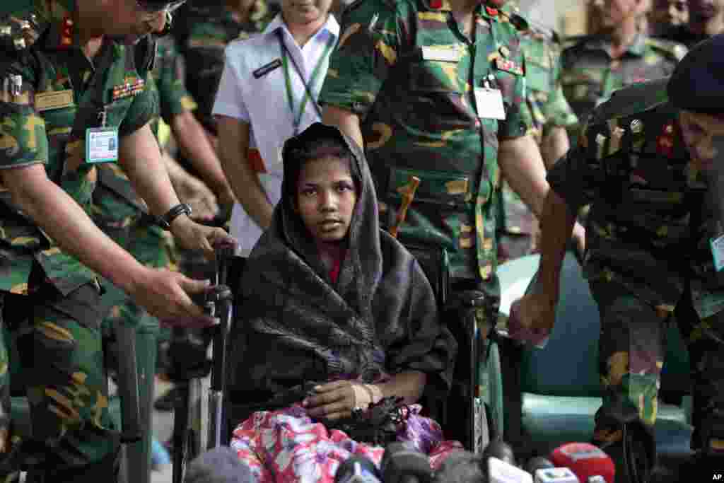 Reshma Begum, center, the 19-year-old seamstress who spent 17 days trapped in the rubble of a collapsed factory building talks to the media at a hospital in Savar, near Dhaka, Bangladesh, May 13, 2013. 