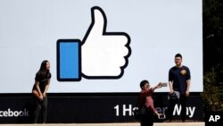 FILE - Visitors take photos in front of the Facebook logo at the company's headquarters, March 28, 2018, in Menlo Park, Calif.
