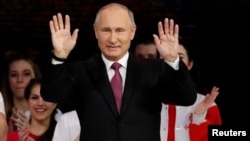 Russian President Vladimir Putin greets the audience at the congress of volunteers in Moscow, Russia Dec. 6, 2017.