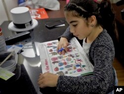 In this Jan. 23, 2018 photo, Yandeliz Neris studies a workbook inside her family's hotel room at the Rodeway Inn in Tampa, Florida, where she's living with her family after Hurricane Maria destroyed their home in Puerto Rico.