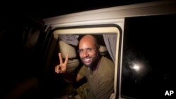 Saif al-Islam, son of Moammar Gadhafi, makes a peace sign before meeting reporters in Tripoli, Libya, Aug. 23, 2011.