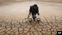 A farmer takes water form a dried-up pond to water his vegetable field on the outskirts of Yingtan, Jiangxi province December 10, 2007. Climate change has been blamed for more frequent droughts in some regions.