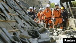 Firefighters walk among collapsed houses caused by an earthquake in Mashiki town, Kumamoto prefecture, southern Japan, in this photo taken by Kyodo, April 15, 2016. (REUTERS/Kyodo)