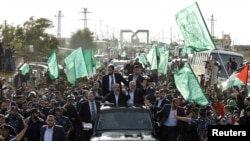 Pemimpin Hamas Khaled Meshaal (kiri), bersama pemimpin senior Hamas Ismail Haniyeh (kanan) malakukan pawai dan melambaikan tangan kepada para pendukungnya setibanya di Gaza (7/12). Warga Palestina memperingati 25 tahun berdirinya kelompok militan Islamis Hamas, hari ini.