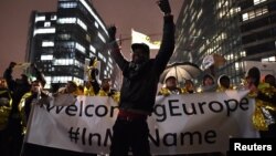 A man raises his hands during a protest in support of a new EU migration policy, a day before an EU leaders' meeting, in Brussels, Belgium, Dec. 13, 2017.