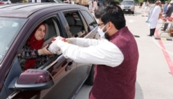 A woman accept treats during a drive-through Eid al-Fitr celebration outside a closed mosque in Plano, Texas, May 24, 2020.