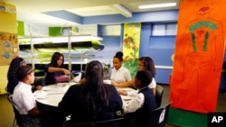 First lady Michelle Obama, center left, pours a smoothie mix on a cup while sitting with students at Philip's Academy Charter School as part of her American Garden Tour visit, Thursday, April 7, 2016, in Newark, N.J. (AP Photo/Julio Cortez)