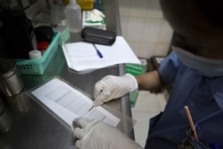 បុគ្គលិកពេទ្យម្នាក់កំពុងធ្វើតេស្តឈាមរកមេរោគគ្រុនឈាម នៅក្នុងអគារព្យាបាលអ្នកជំងឺនៃមន្ទីរពេទ្យកុមារអង្គរ។