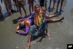 A Rohingya woman, who crossed over from Myanmar into Bangladesh, shouts for help as a relative lies unconscious after the boat they were traveling in capsized minutes before reaching shore at Shah Porir Dwip, Bangladesh, Sept. 14, 2017.
