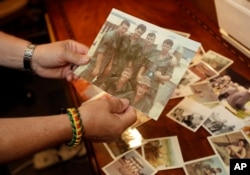 In a photo from June 9, 2017, in South Haven, Mich., former Army medic James McCloughan shows photos of himself and fellow soldiers in Vietnam.