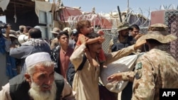 Pakistani soldiers, right, check stranded Afghan nationals at the Pakistan-Afghanistan border crossing point in Chaman on Aug. 13, 2021, after the Taliban took control of the Afghan border town in a rapid offensive across the country. 
